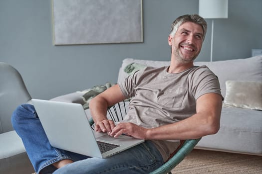 Young attractive smiling guy is browsing at his laptop