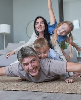 Young family of four having fun at home smiling