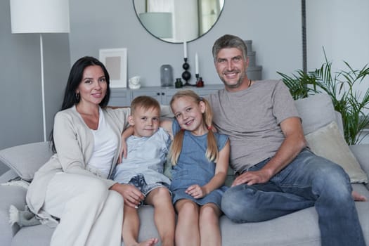 Family sitting in living room smiling at home