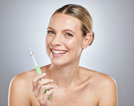 Face, teeth and woman with toothbrush in studio isolated on a gray background. Oral health, dental veneers and female model getting ready to brush with toothpaste for hygiene, cleaning and wellness