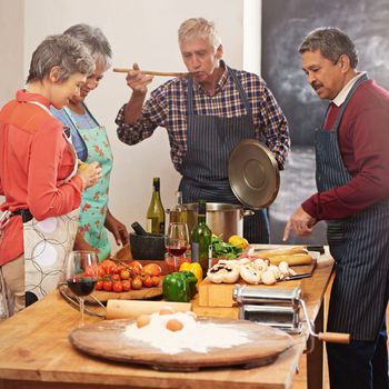 The secret is one heaping spoon of love. a group of seniors cooking in the kitchen