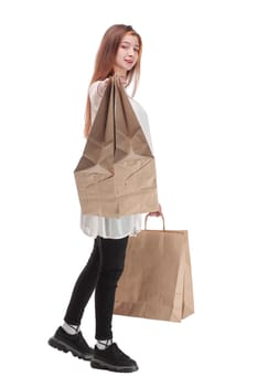 Studio photo of pretty woman walking, carrying paper shopping bags. White background.