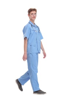Full length portrait of young caucasian with stethoscope walking doctor isolated on white