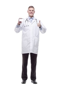 in full growth. smiling doctor showing his visiting card. isolated on a white background.