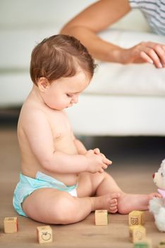 Fun at one. an adorable baby girl playing with wooden blocks at home