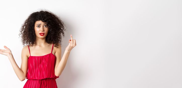 Annoyed caucasian woman in red dress, showing finger without wedding ring, arguing about marriage, standing pissed-off on white background.