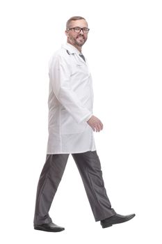 full-length. Mature male doctor striding forward. isolated on a white background.