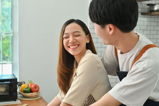 Affectionate asian man and smiling woman preparing homemade pastry, spending time in cozy modern kitchen at home.
