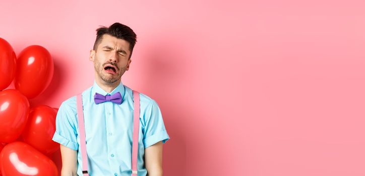 Valentines concept. Sad and heartbroken man crying over break-up, being cheated on lovers day, sobbing and feeling lonely, standing on pink background.