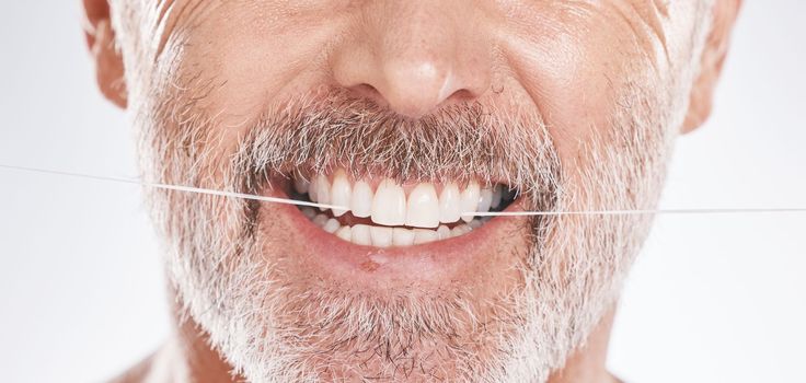 Dental, floss and mouth of senior man in studio isolated on a gray background. Hygiene, cleaning and elderly male model with product flossing teeth for oral wellness, tooth care and healthy gums