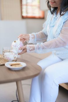 Portrait of an elderly Asian woman drinking healthy tea while eating snack
