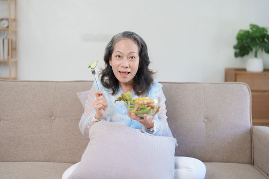 Portrait of an elderly Asian woman taking care of her health by eating salad