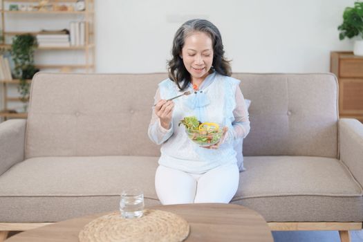 Portrait of an elderly Asian woman taking care of her health by eating salad