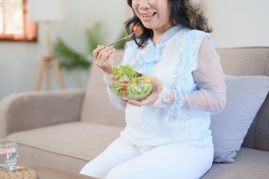 Portrait of an elderly Asian woman taking care of her health by eating salad