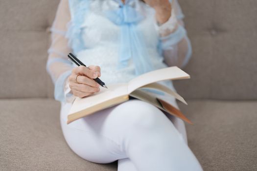 Portrait of an elderly Asian woman holding a notebook eating snacks and drinking tea