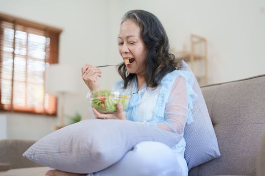 Portrait of an elderly Asian woman taking care of her health by eating salad