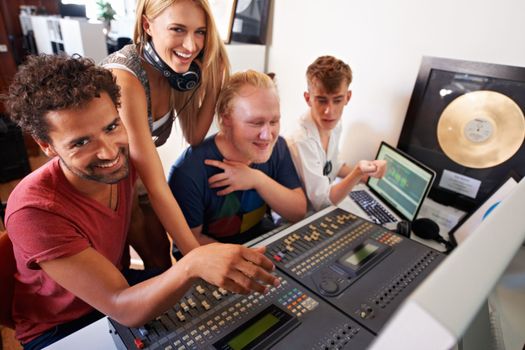 Creating a hit takes time...Four young audio engineers working on a mixing desk
