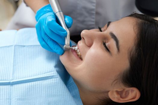 Young woman getting her teeth polished in modern dental clinic