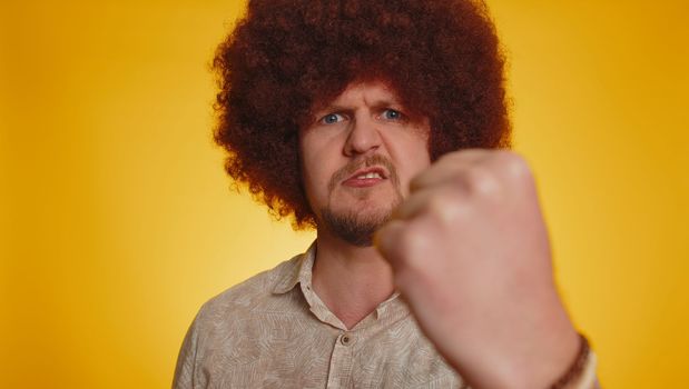 Quarrel. Displeased man with lush Afro hairstyle gesturing hands with irritation and displeasure, blaming scolding for failure, asking why this happened. Young hipster guy on yellow studio background