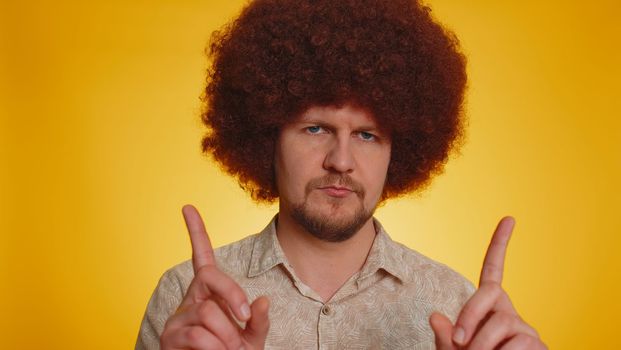 Displeased upset bearded man with afro hairstyle reacting to unpleasant awful idea, dissatisfied with bad quality, wave hand, shake head No, dismiss idea, dont like proposal. Guy on yellow background