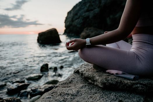 Young woman with black hair, fitness instructor in pink sports leggings and tops, doing pilates on yoga mat with magic pilates ring by the sea on the beach. Female fitness daily yoga concept