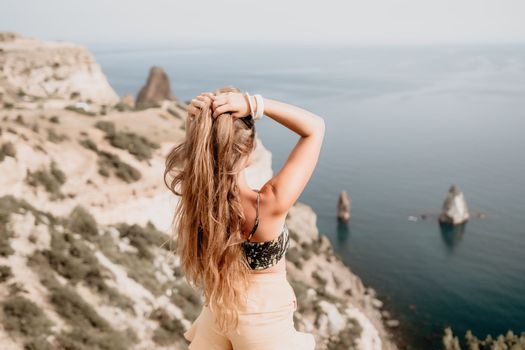 Woman travel sea. Happy tourist taking picture outdoors for memories. Woman traveler looks at the edge of the cliff on the sea bay of mountains, sharing travel adventure journey.