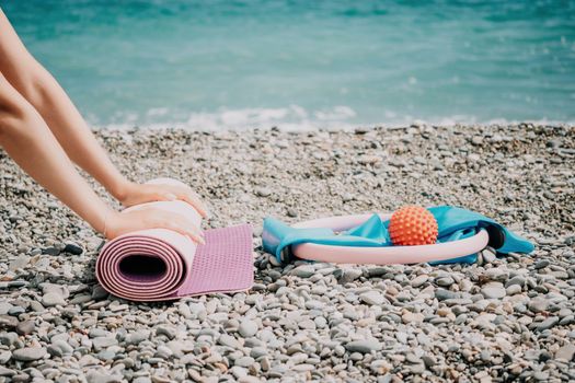 Young woman with long hair in white swimsuit and boho style braclets practicing outdoors on yoga mat by the sea on a sunset. Women's yoga fitness routine. Healthy lifestyle, harmony and meditation