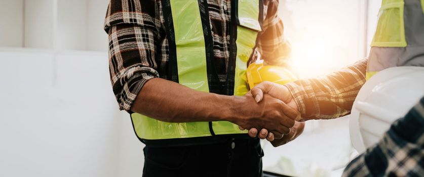 Architect and engineer construction workers shaking hands while working for teamwork and cooperation concept after finish an agreement in the office construction site.