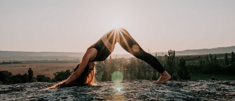 Well looking middle aged woman with long hair, fitness instructor in leggings and tops doing stretching and pilates on the rock near forest. Female fitness yoga routine concept. Healthy lifestyle.