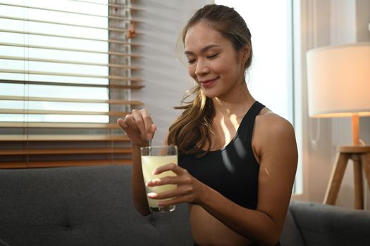 Attractive sporty woman drinking collagen supplements after exercise. Natural supplement for skin beauty and bone health.