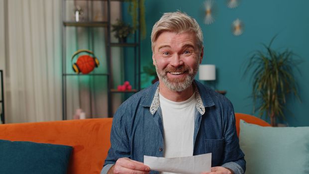Happy man open envelope letter, reading it. Career growth advance promotion, bank loan approve, successful admission to university monetary award long-awaited invitation great news, lottery game win