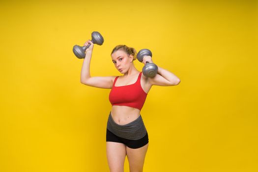 Strong sportswoman in boxing gloves prepared high kick. Isolated on a white, red, yellow background