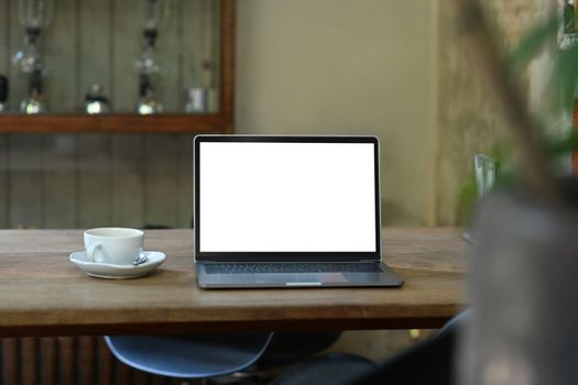 Mock up laptop and cup of coffee on rustic wooden table. Empty screen for your advertise design.