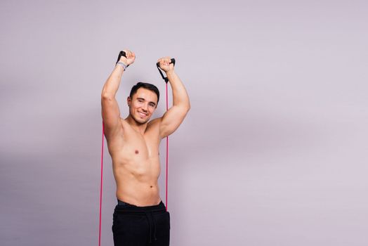 Athletic man skipping with jump rope on grey background. Best cardio workout