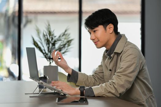 Side view of male manager having video call with diverse colleagues on online briefing.