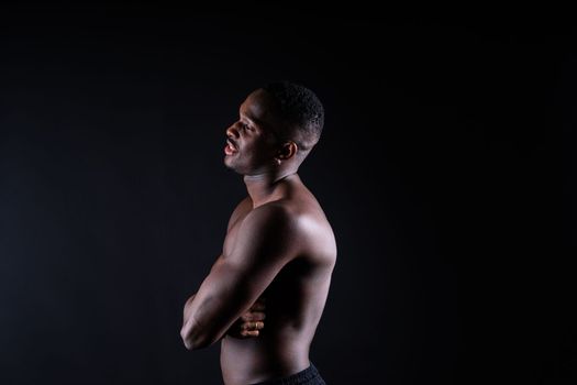 Portrait of athletic african american man topless, black background