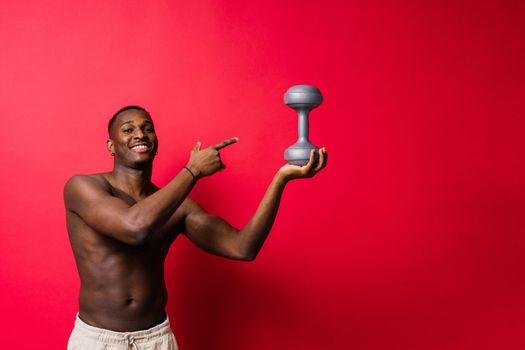 Portrait of happy african man with dumbbells over red background