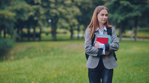 A smiling student with books in the park