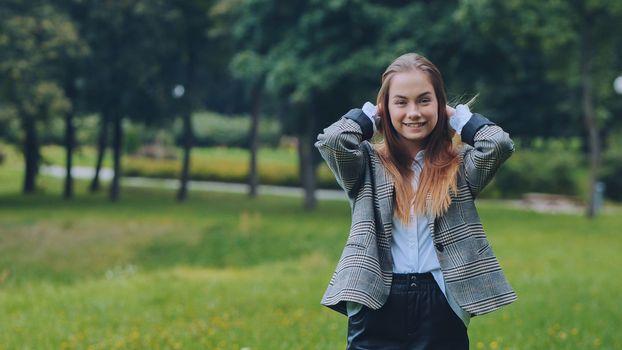 A young girl in a jacket poses in a park in the summer
