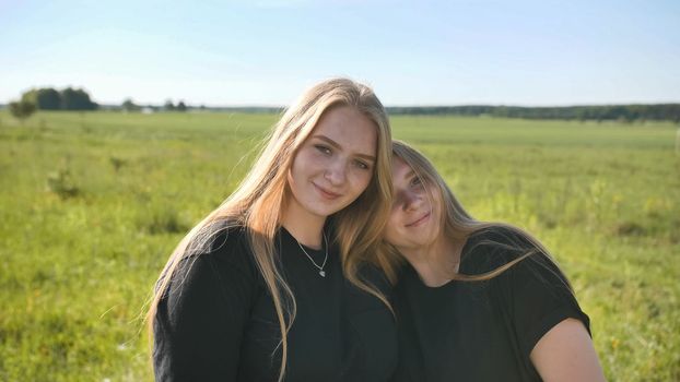 Portrait of two twin sisters in the field on a warm summer day.