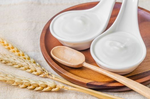Greek yogurt in a bowl and dry barley on tablecloth.
