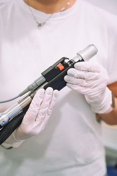 Close up shot of gloved hand with the laser hair removal machine's handpiece. Alexandrite laser techhnology removing hair. Beauty technology concept