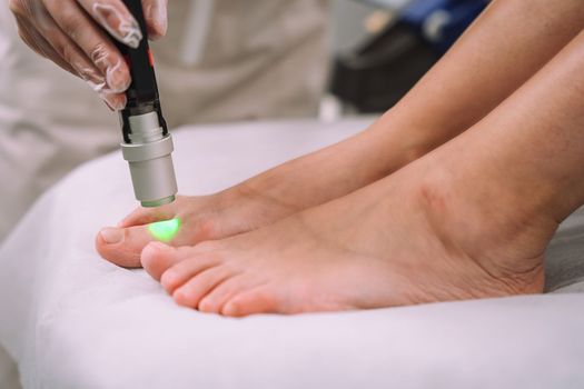 Close up shot of gloved hand with the laser hair removal machine's handpiece along woman leg. Alexandrite laser techhnology removing hair. Beauty procedureBeauty technology concept