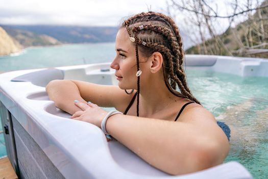 Take time for yourself. Outdoor swimsuit with mountain and sea views. A woman in a black swimsuit is relaxing in the hotel pool, admiring the view.