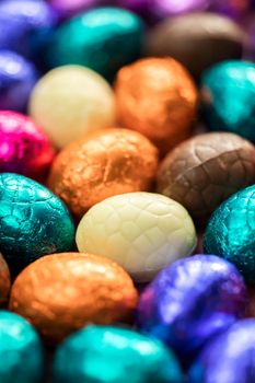 Big pile of colorful wrapped chocolate easter eggs, shiny festive Easter concept, Happy easter close-up candy sweets concept macro various colors