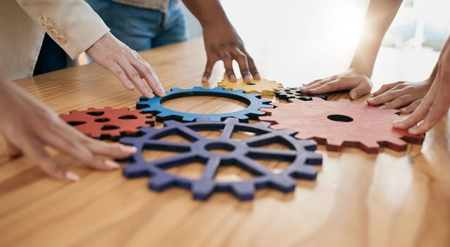 Hands, collaboration and gear with a business team working together in synergy for innovation at a workshop. Meeting, teamwork and creative with a man and woman employee group at work in the office.