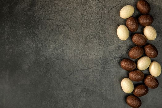 Composition with chocolate Easter eggs on dark background copy space top view. Happy Easter holiday concept sweets