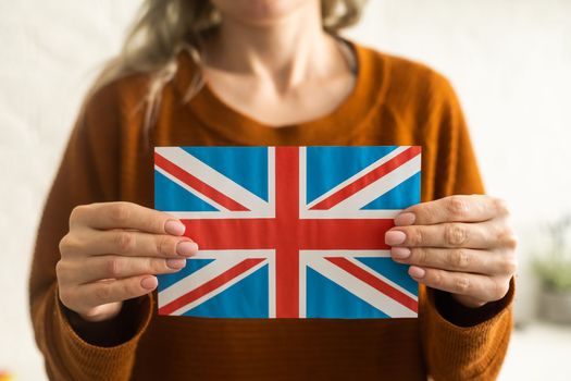 Hand holding flag of UK, isolated on white background.