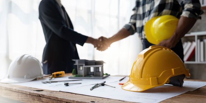 Shaking hands, Blueprints architects and building engineers talking meeting and planning will chronicle the design and technical aspects of a new house construction, renovation remodeling.