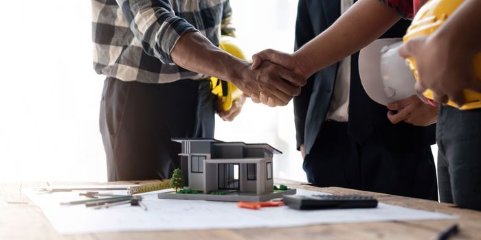 Shaking hands, Blueprints architects and building engineers talking meeting and planning will chronicle the design and technical aspects of a new house construction, renovation remodeling